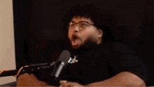 a man with a beard is sitting in front of a microphone .