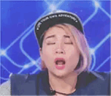 a woman with pink hair and a black hat is making a funny face .