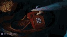 a man is laying in bed talking on a red phone with machinima written on the bottom