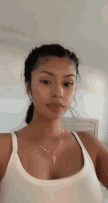 the woman is wearing a white tank top and a necklace .