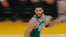 a basketball player in a green jersey is running on the court