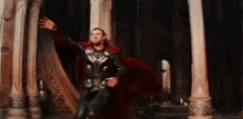a man in a superhero costume is standing in a room between two columns .
