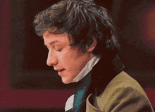 a man with curly hair is wearing a green jacket and a scarf