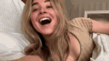 a woman is laying on a bed with her mouth open and laughing .