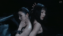 a woman is looking at herself in a mirror while another woman adjusts her hair .