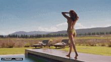 a woman in a bikini is standing next to a swimming pool with the words pranay varma below her