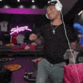 a man wearing headphones is dancing in a room with a number 15 jersey on the wall