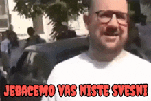 a man wearing glasses and a white shirt with the words jebacemo vas niste svesni