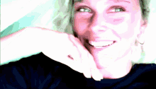 a woman is smiling with her hand on her face