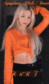 a woman with long blonde hair is wearing an orange sweater and black skirt .