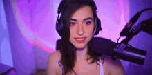 a woman wearing headphones is standing in front of a microphone and smiling .