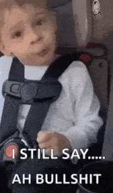 a young boy is sitting in a car seat and making a funny face .