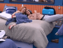two women are laying on a bed in a room .