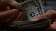 a person is holding a stack of 100 dollar bills in their hand