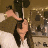 a woman is drinking a bottle of wine in front of a mirror with the letter p on it