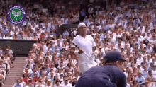 a man in a white shirt is holding a tennis racquet in front of a crowd at the wimbledon tennis championship