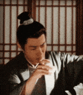 a man with a bun is drinking from a cup