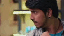 a close up of a man 's face with a blue shirt and earrings