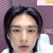 a close up of a young man 's face with long hair and earrings .