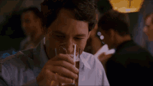 a man in a blue shirt is drinking a beer