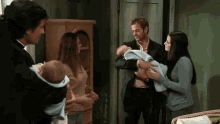 a man in a suit holds a baby in his arms while a woman holds another baby