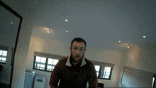 a man with a beard is standing in a room with a mirror