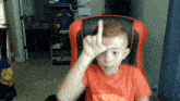 a young boy sitting in an orange chair with a sign that says blues on it