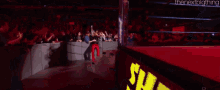 a crowd of people watching a wrestling match with a sign that says trent misses out