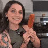 a woman holding a fried chicken on a stick in front of a lg stove