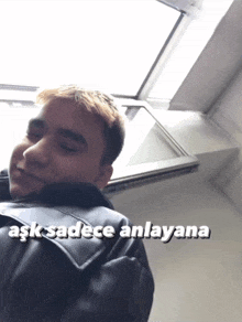 a man in a black jacket with the words ask sadece anlayana on the bottom right