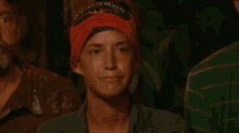 a woman wearing a red bandana is making a funny face while sitting in a crowd of people .