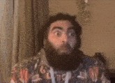 a man with a beard wearing a floral shirt is making a surprised face .