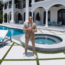a man in a suit is standing in front of a large house