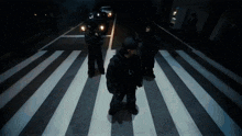 a group of people standing on a zebra crossing at night