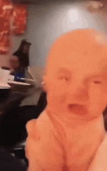 a baby is crying in a restaurant with a woman behind him