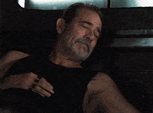 a man with a beard wearing a black tank top has a tattoo on his arm