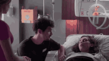 a man stands next to a woman in a hospital bed with an oxygen mask on her face