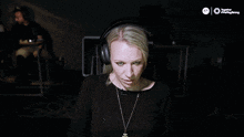 a woman wearing headphones holds her fist in the air in front of a two-player logo