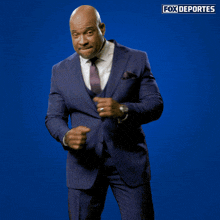 a man in a suit and tie is dancing in front of a blue background with fox deportes written on it