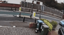 a blue car is driving down a street next to a fence