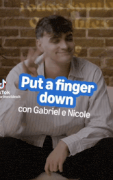 a man is sitting in front of a brick wall with the caption put a finger down