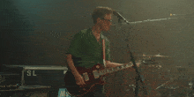 a man in a green shirt is singing into a microphone while playing a guitar