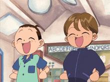 two boys are laughing in front of a chalkboard with the letters abcdefghijklmnopqrs on it