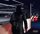 a man in a black coat walks out of a wrestling ring with the tnlw logo on the bottom