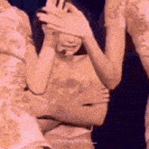 a woman is covering her face with her hands while standing next to a man .