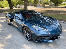 a blue sports car is parked in a parking lot with trees in the background