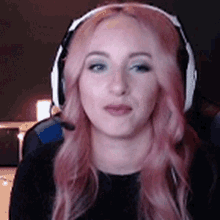 a woman with pink hair and headphones is sitting in a chair .