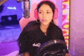 a woman wearing pink headphones and a black shirt is sitting in a pink chair .
