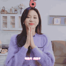 a woman wearing a purple sweater and a number 6 headband