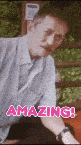 a man with a mustache is sitting in front of a sign that reads amazing